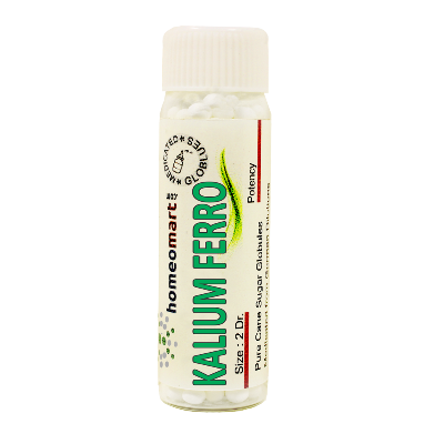 A bottle of Kalium Ferrocyanatum homeopathy pills, labeled 'HOMEOMART' and 'KALIUM FERROCYANATUM'. The bottle has a white and green label, with a white cap and contains several white pills.