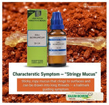 Kali Bichromicum homeopathic medicine bottle and box on a red clay background with text about stringy mucus.